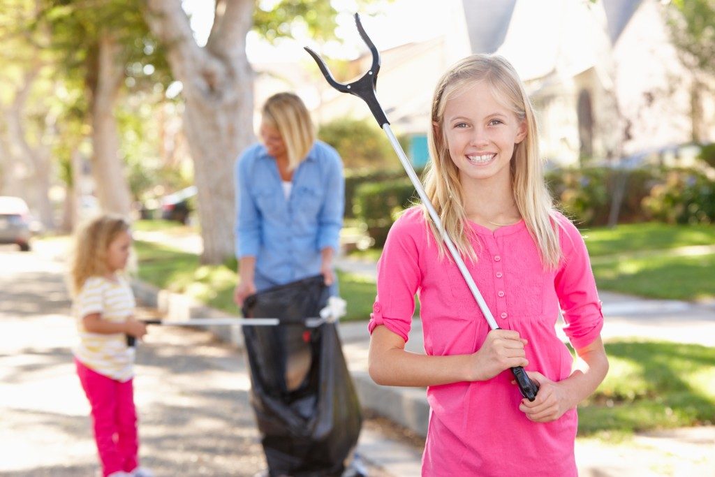 mother and her daughters picking up trash around the suburbs