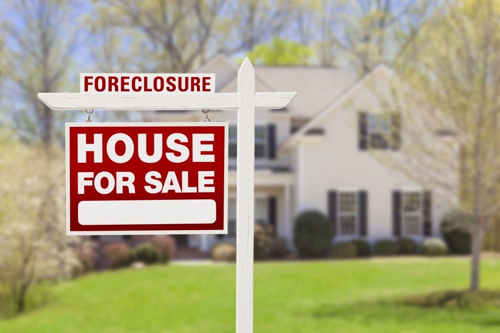Red Foreclosure Home For Sale Real Estate Sign in Front of House.